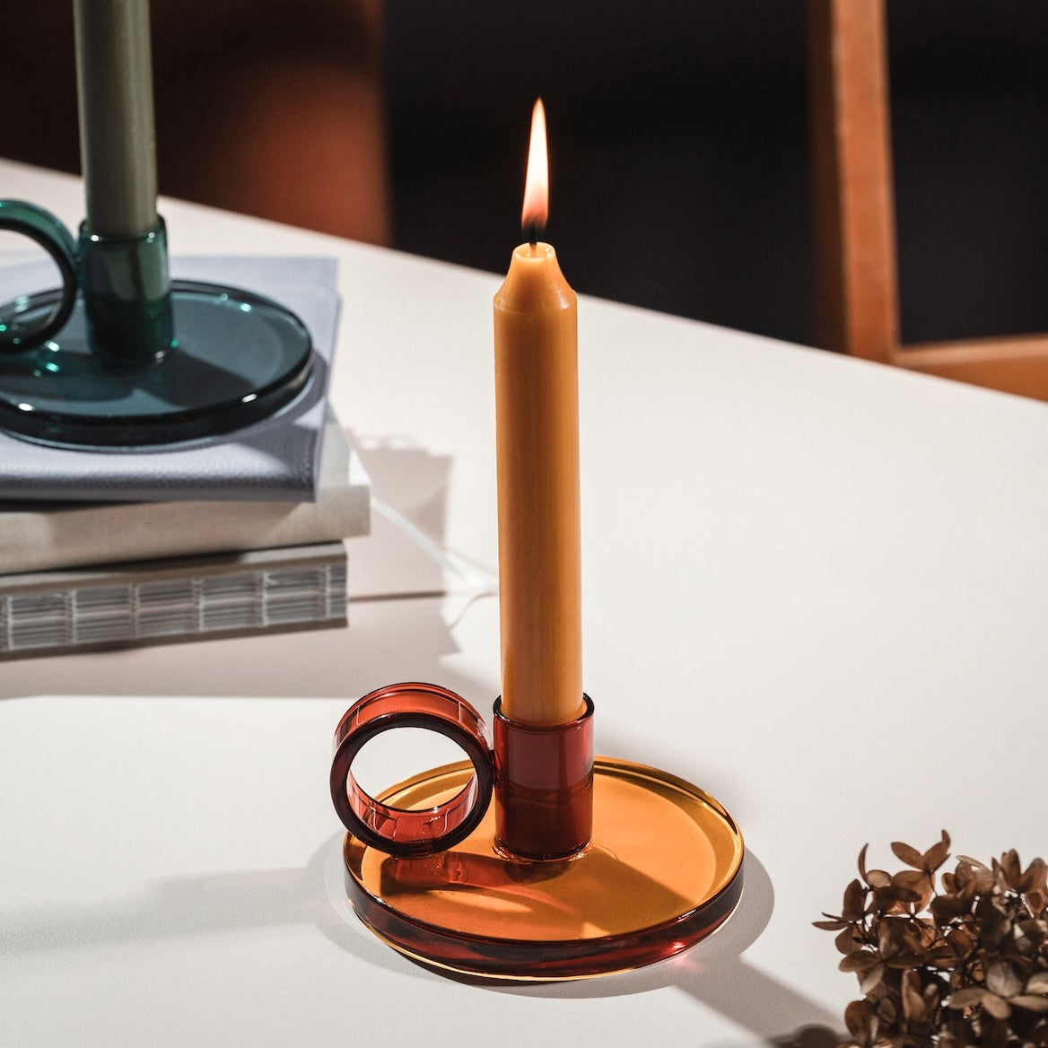 Loop Candlestick holder in amber on a white surface with a blurred background