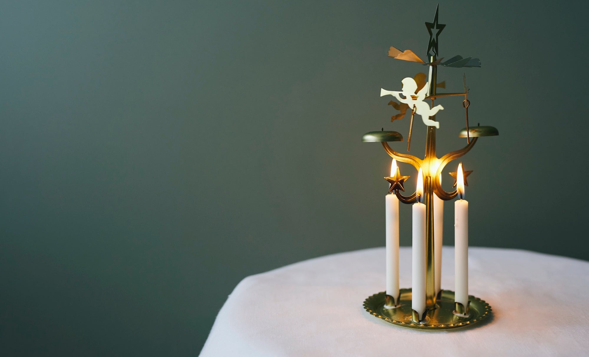 Havi Angel Bell Candles, lighting an Angel Rotary Christmas Chime. Pictures on a table with a white tablecloth