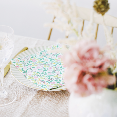 William Morris&#39; Clover Design in Pink on a Havi Paper Napkin.     Shown on a dinner plate next to flowers