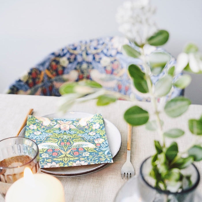 Strawberry Thief paper napkins shown on a plate in a table setting.   William Morris&#39;s iconic design together with Havi manufacturing in Finland