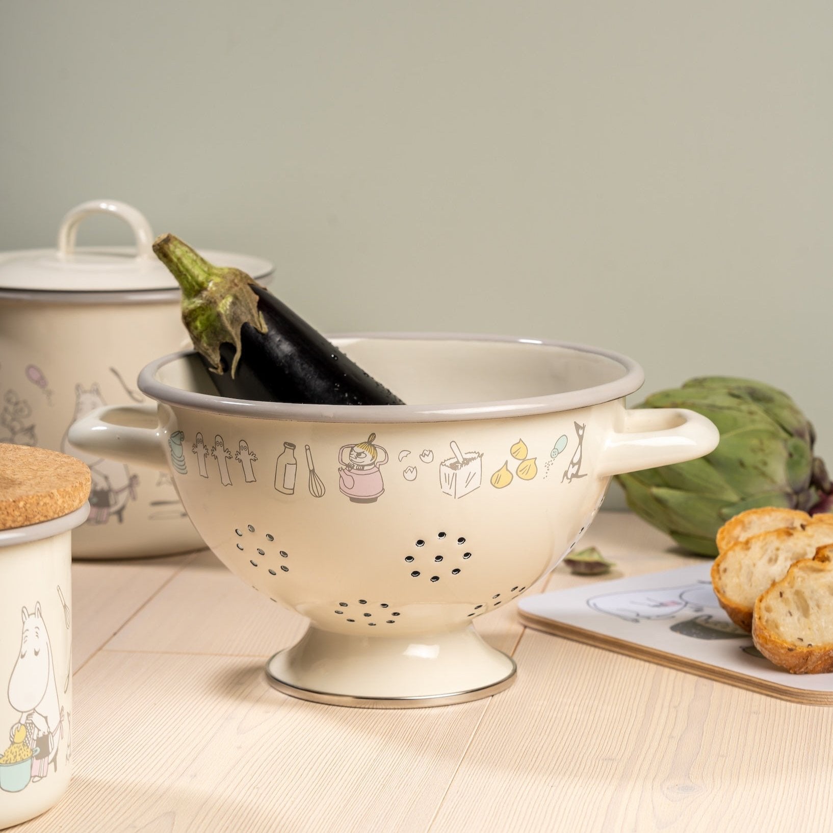 Moomin Bon Appétit enamel colander shown with an aubergine inside, next to other Bon Appétit Muurla Design kitchen items 