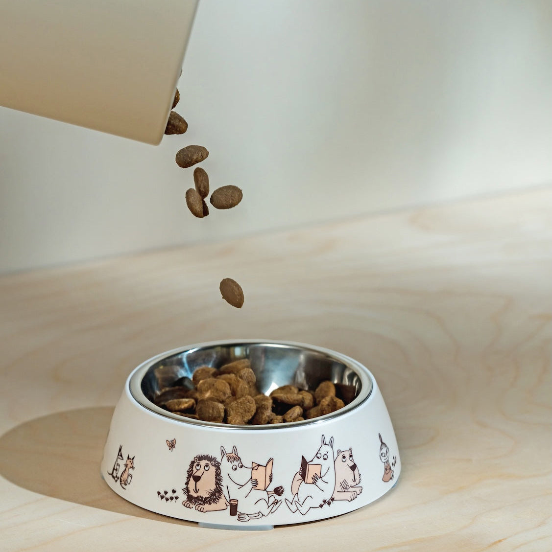 Dog food bowl with Moomin Moments illustrations on a wooden surface
