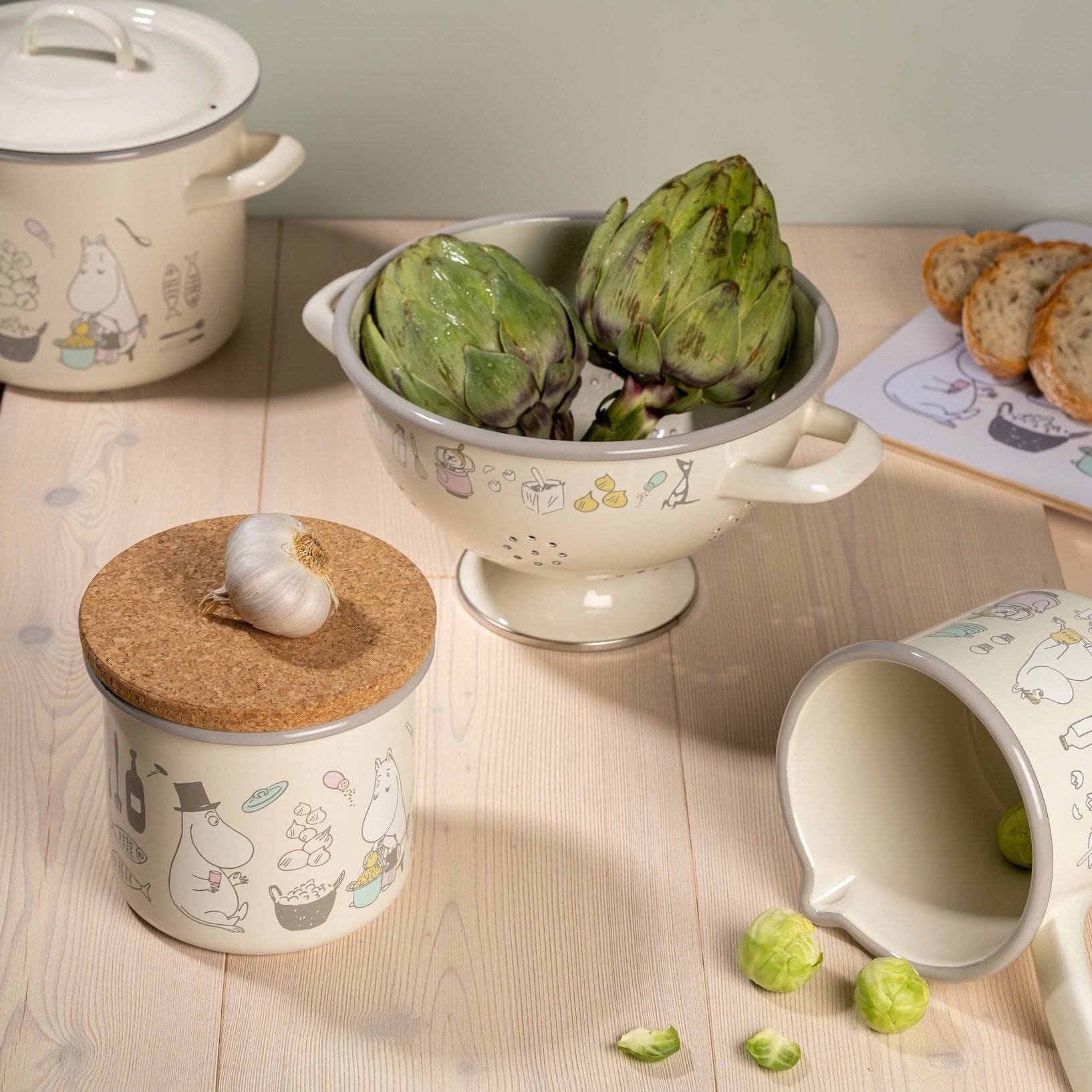 Moomin Bon Appetit Saucepan filled with dried pasta, placed on a chopping board next to some sliced bread