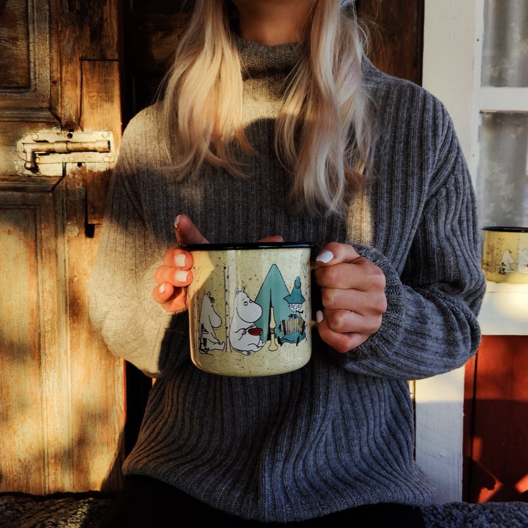 Moomin Campers Enamel Mug held in both hands by a lady outside, wearing a winter jumper 