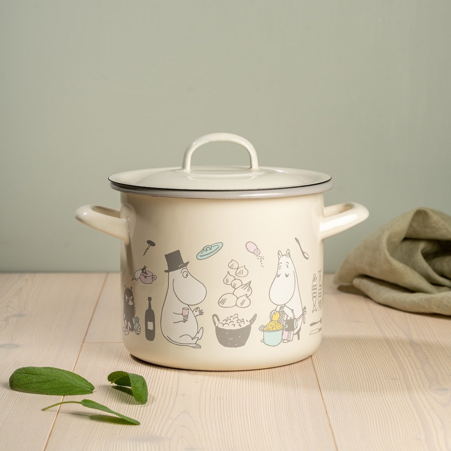 Moomin Bon Appetit Pot with Lid pictures next to some Sage leaves and a sage coloured kitchen towel