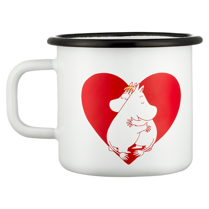 Mug with a heart design and Moomin characters on a table with a cake and red checkered cloth in the background.