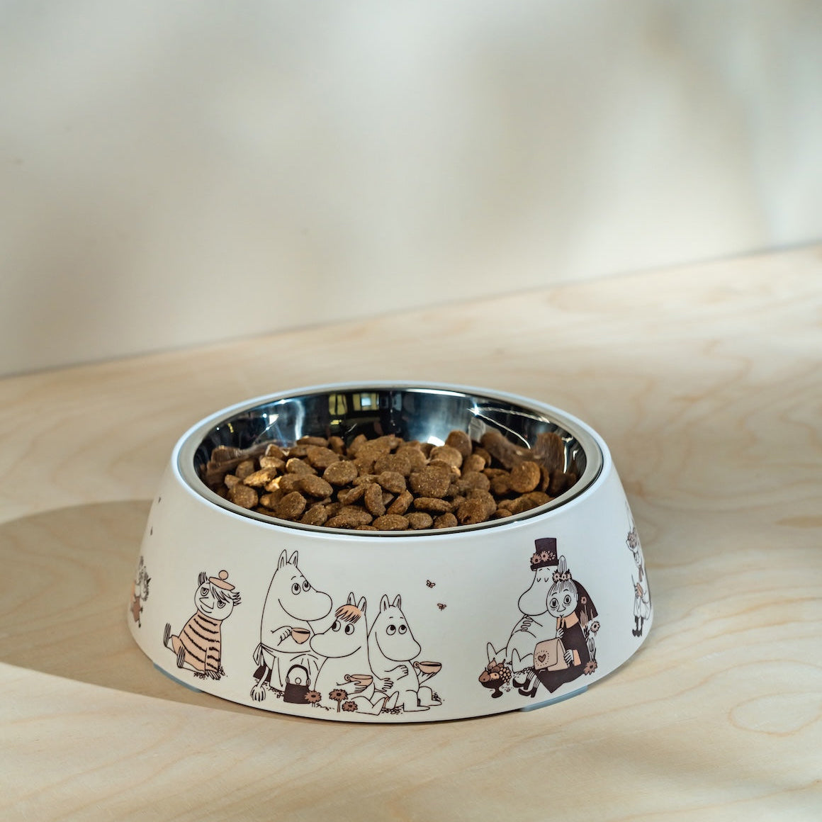 Dog bowl with Moomin cartoon characters on a wooden surface
