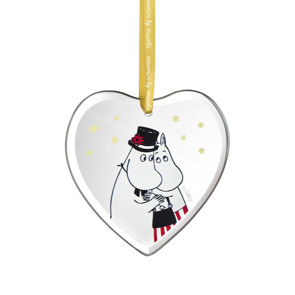 Heart-shaped Christmas ornament with a Moomin characters on a tree branch against a dark background