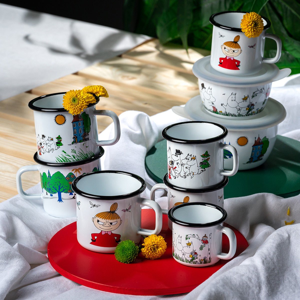 Muurla Design&#39;s Colours Collection of enamel mugs and bowls, with the key Moomin Characters on a white enamel background.