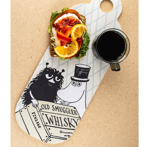 The Adventurer Moominpappa Chop and Serve Board, shown together with a cup of black coffee and an open sandwich