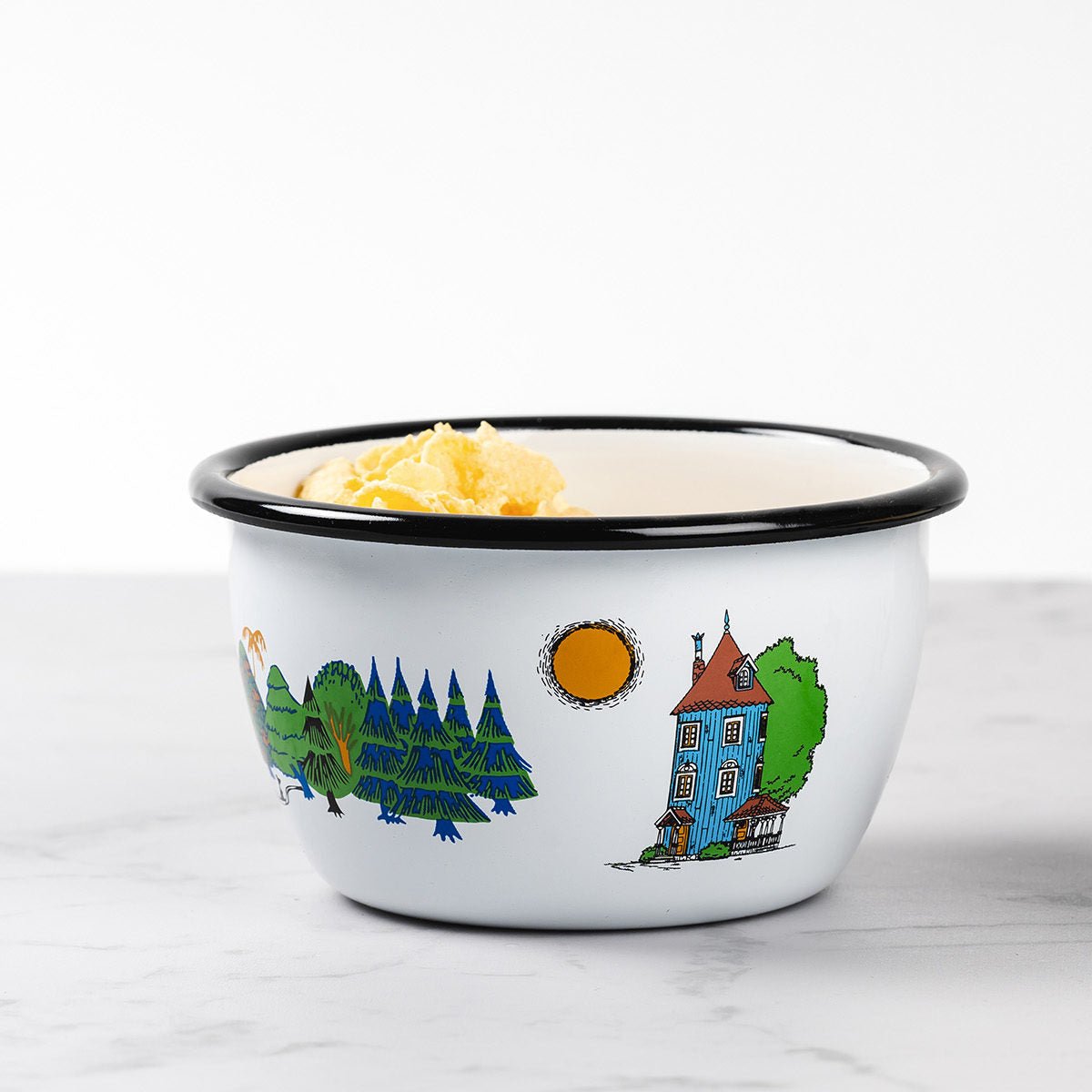 Moomin Valley Enamel Bowl by Muurla Design filled with cereal.   All the key Moomin Valley characters and landscapes are shown on the side of the bowl