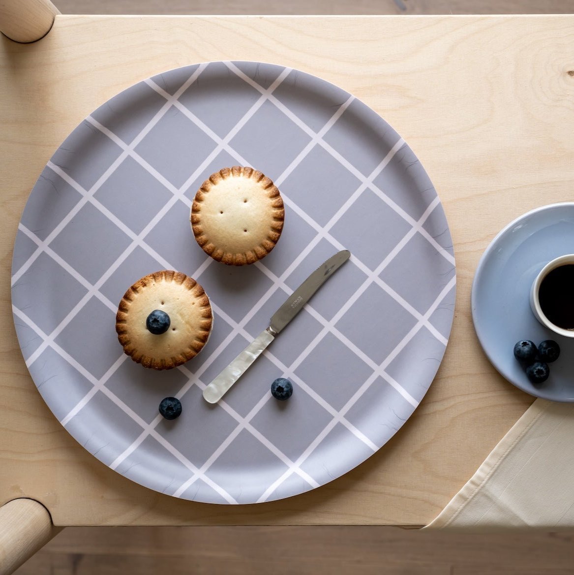 Muurla Grey Checks and Stripes Wooden Round Tray, pictured with Fruit Tarts on top, next to berries and a knife. A cup of Black coffee is next to the tray