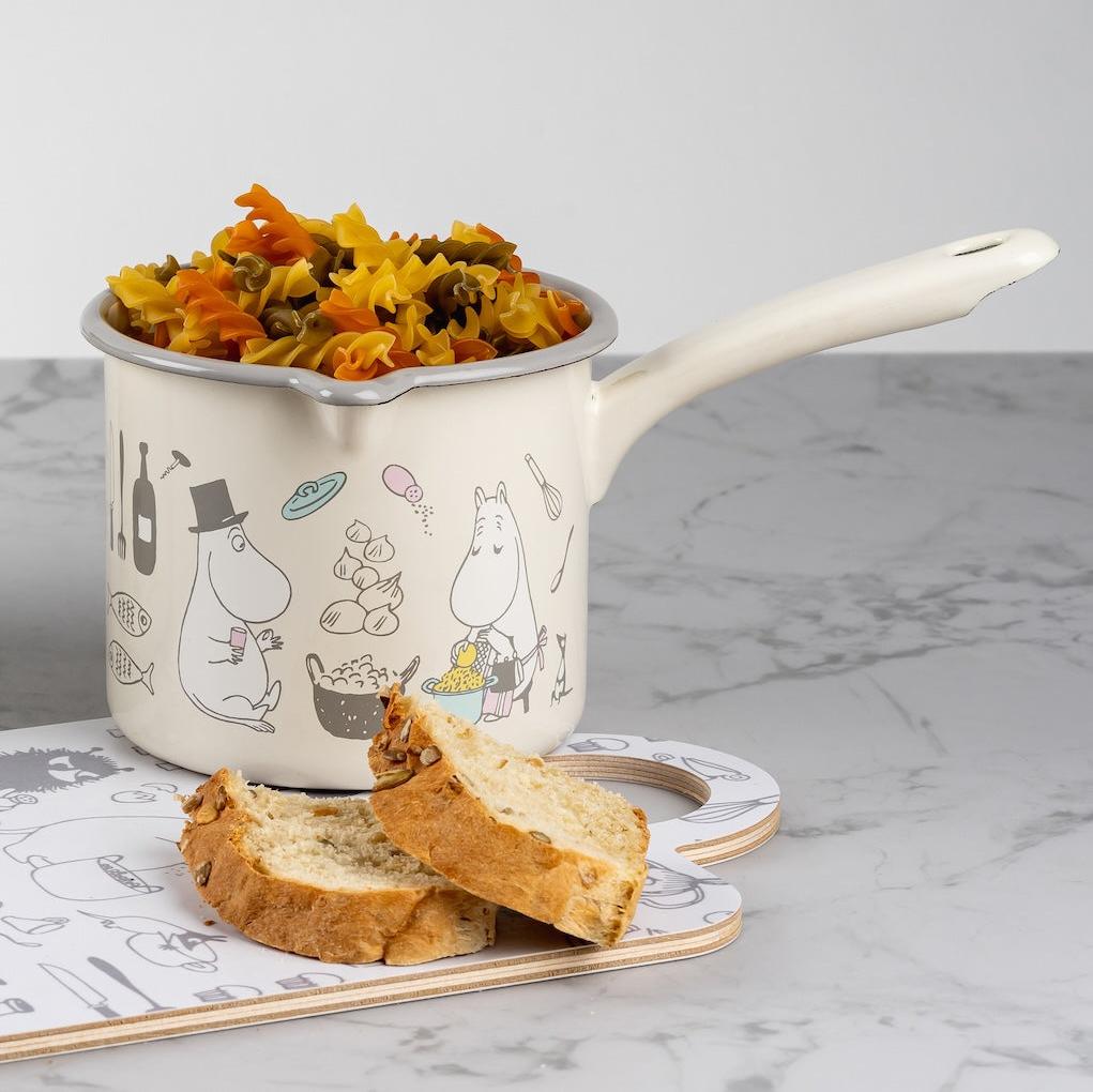 Moomin Bon Appetit Saucepan filled with dried pasta, placed on a chopping board next to some sliced bread