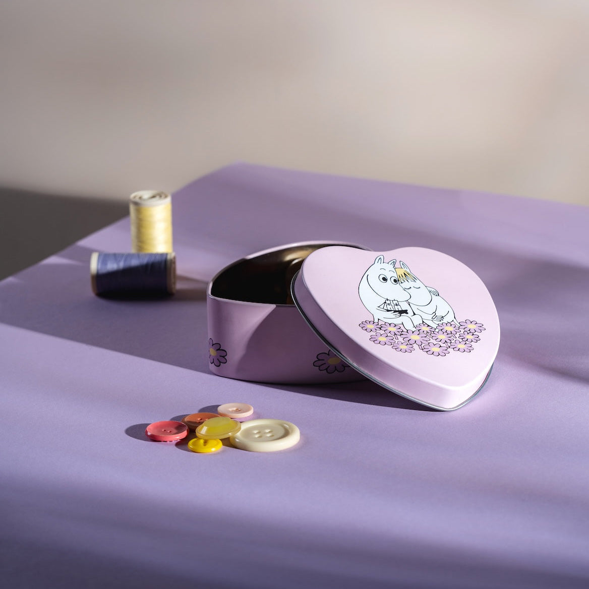 Moomin Heart-shaped tin with a cartoon character on a purple surface with colorful buttons.