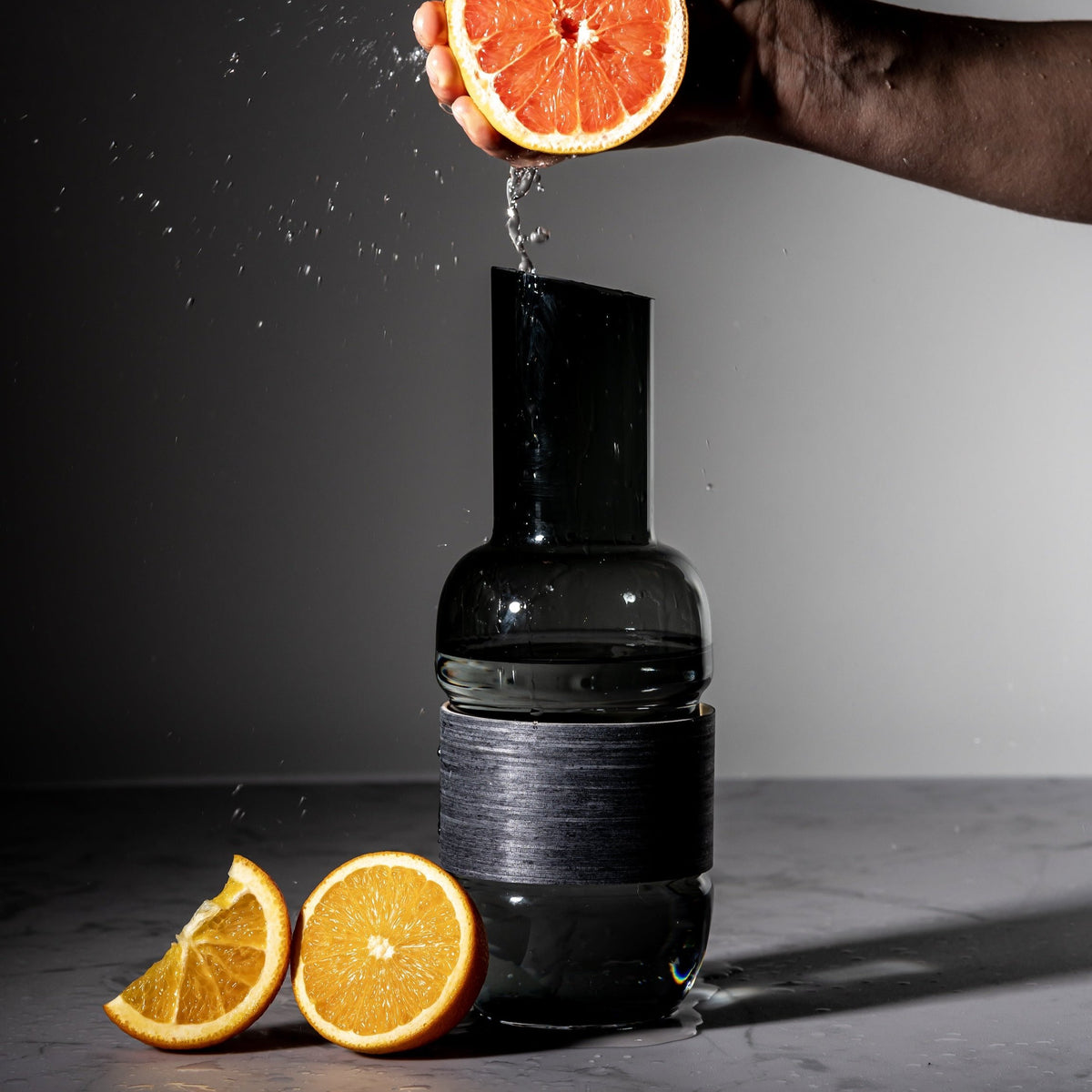 Orange being squeezed into a Veneer Grey / Charcoal Pitcher by Muurla Design 