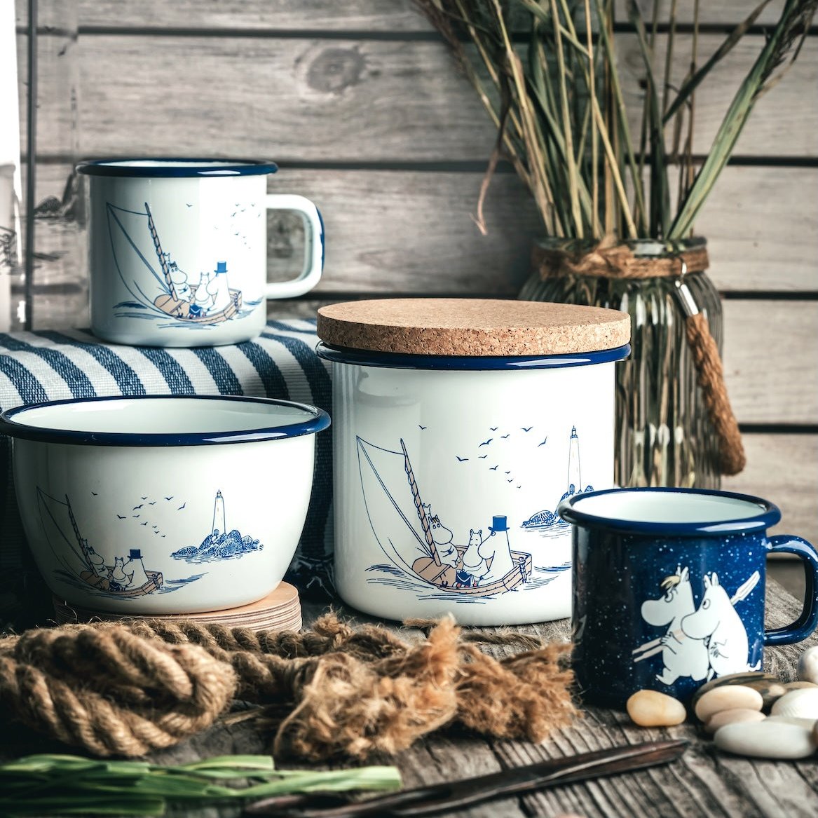 Moomin Sailors Enamel Jar with Cork Lid.  Shown with its Cork lid tilted, sitting on wood decking.