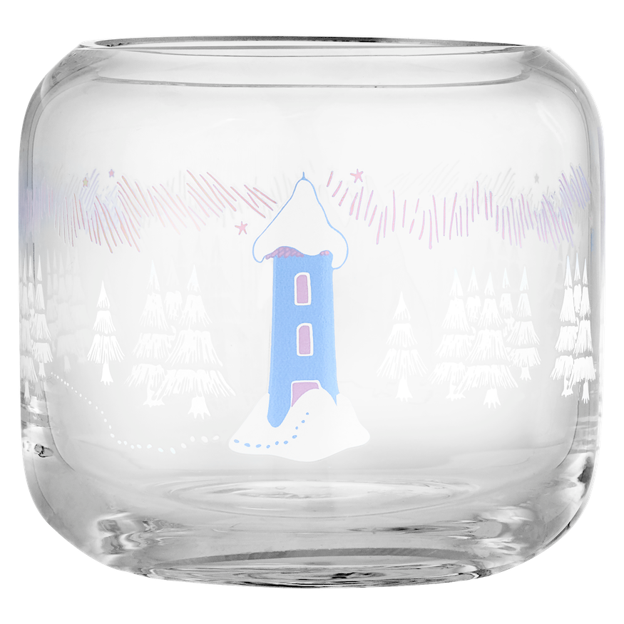 A clear glass tumbler with a Moomin winter forest illustration sits on a round wooden side table next to wrapped gift boxes tied with a purple ribbon and a small sprig of pine needles, against a soft lavender background.