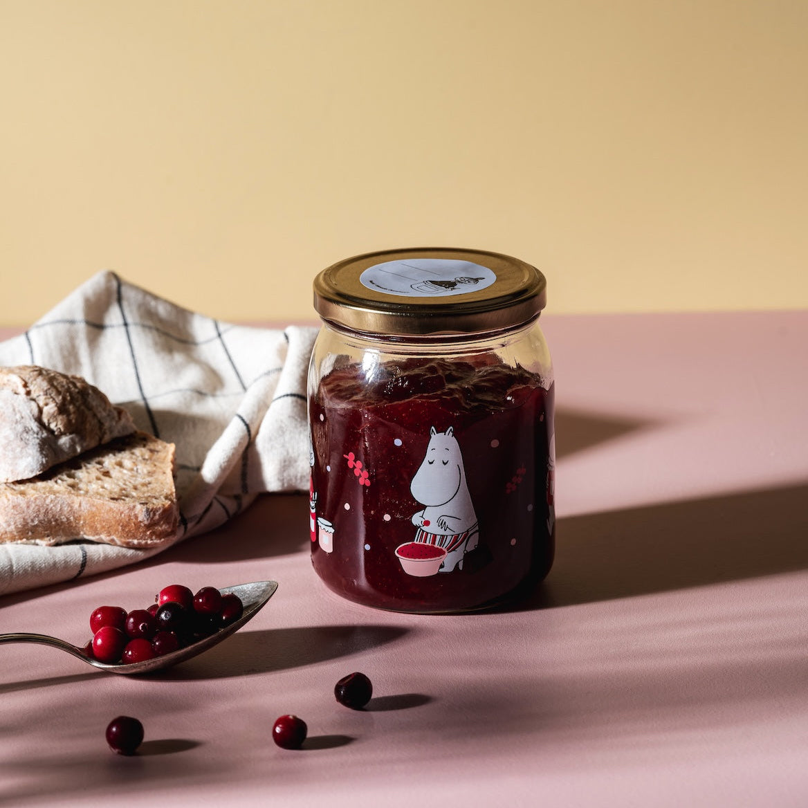 Moomin Glass Jar Berries 0.5L shown full of Berry Jam, next to a spoon also full of fresh berries