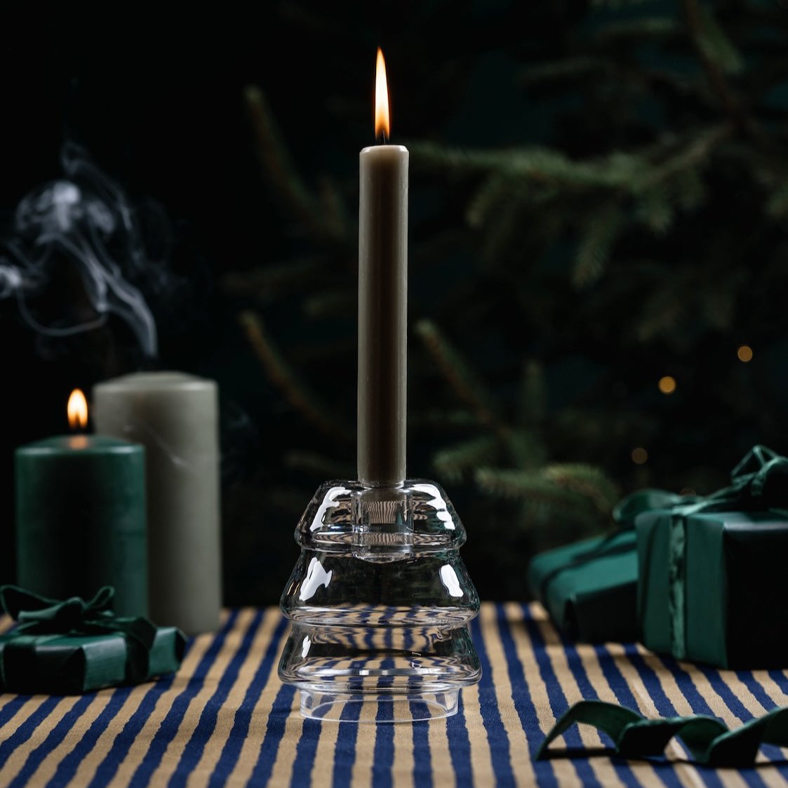 Muurla Christmas Tree Glass Candle Holder, shown on  blue tablecloth with Christmas decorations and gifts in the background.
