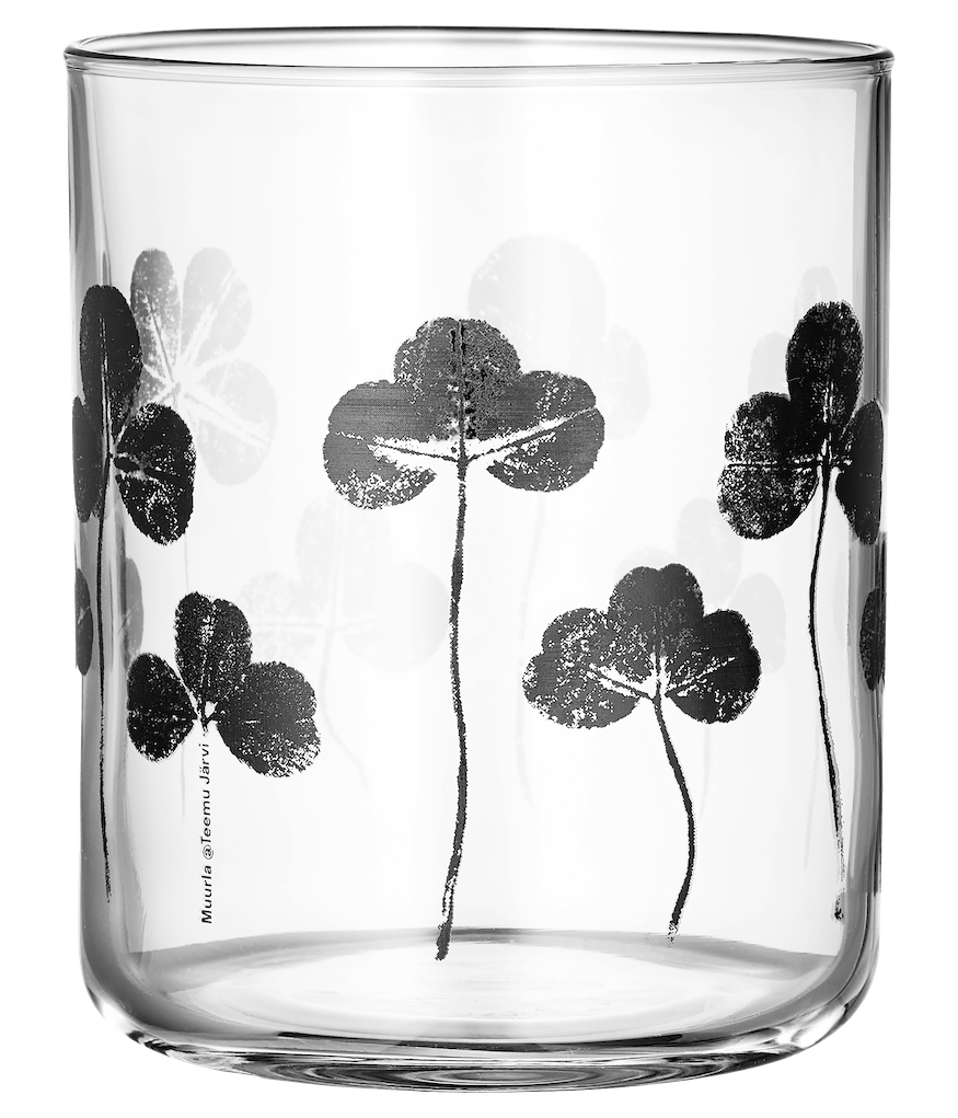 Clear glass with black clover design on a light surface with blurred background.  Made by Muurla Design