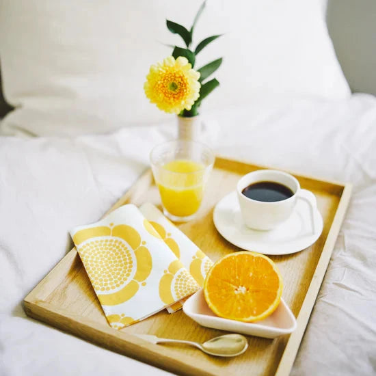 Breakfast tray with coffee, orange juice, and fruit on a bed