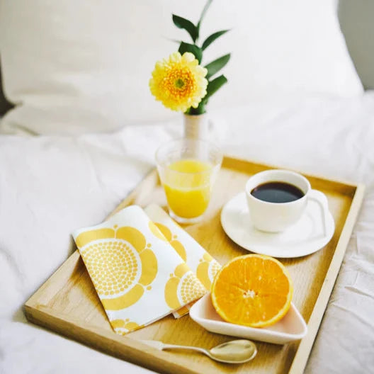Breakfast tray with coffee, orange juice, and fruit on a bed