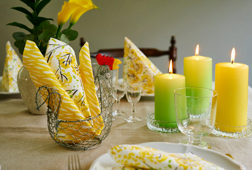 Havi Green Candles and Havi Yellow napkins in a table setting with white dinner plates and clear glassware