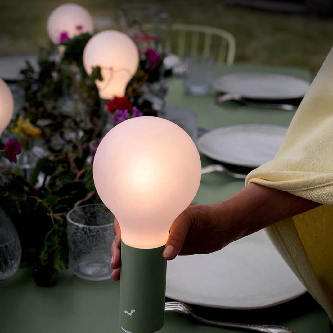 Aplo Lamp in Cactus by Fermob, being placed along the centre of a Fermob Outdoor Dining Table