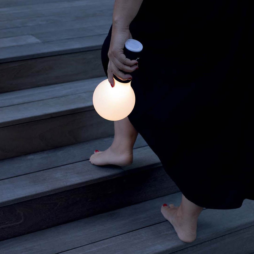 Fermob Aplo portable lamp being carried by a lady at dusk