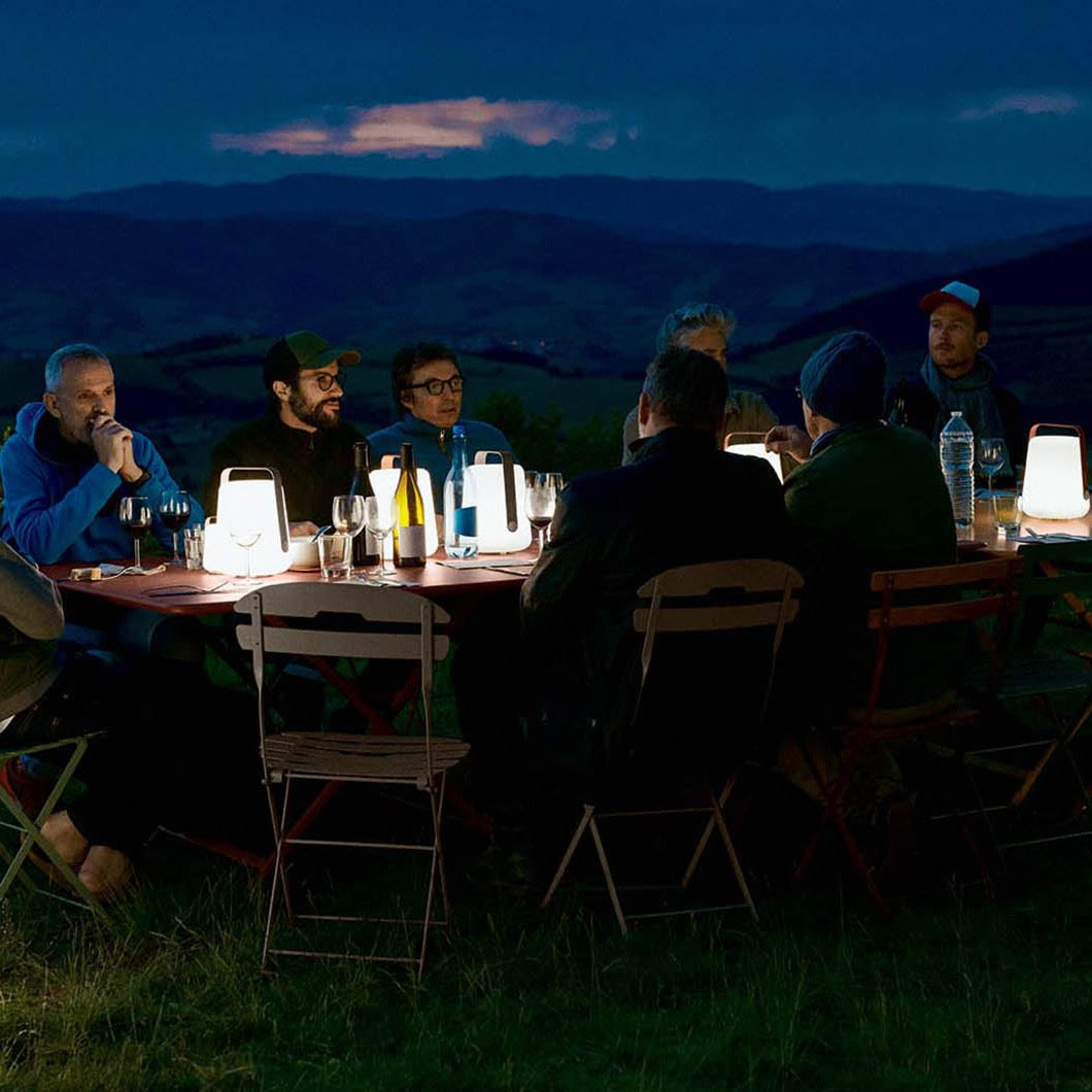 4 Fermob Balad 25cm LED Lights on a long table illuminating a countryside dinner 