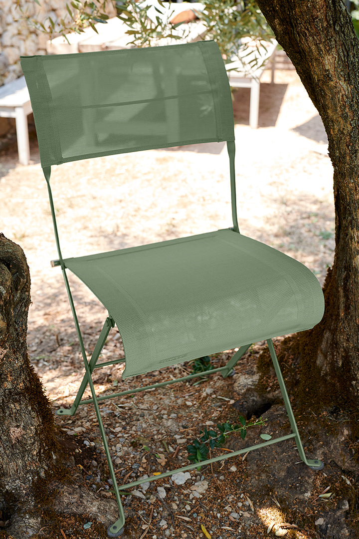 Cactus Batyline Outdoor Fabric on a Fermob Dune Premium Chair outside at the foot of trees. 