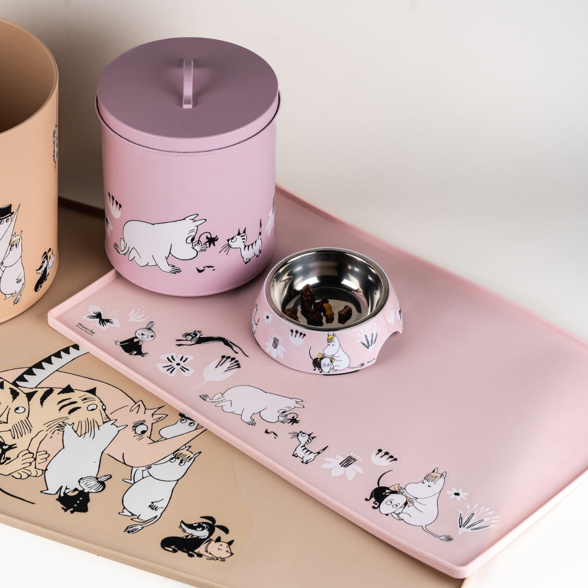 Pink Pet Feeding mat by Muurla Design, together with a storage tin and pet bowl.  All with Moomin designs