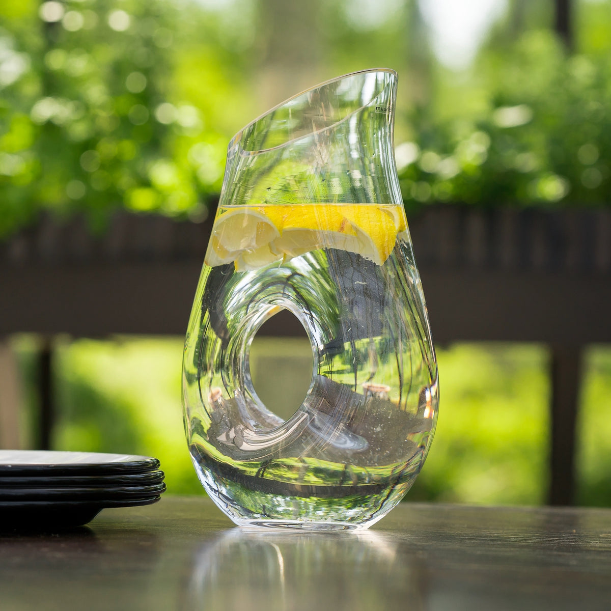 Muurla O-Pitcher on an outdoor table, filled with water and lemons